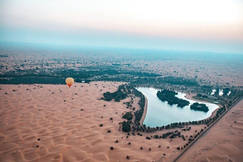 Un paysage désertique avec une étendue d’eau importante, une montgolfière et une ville lointaine. 3