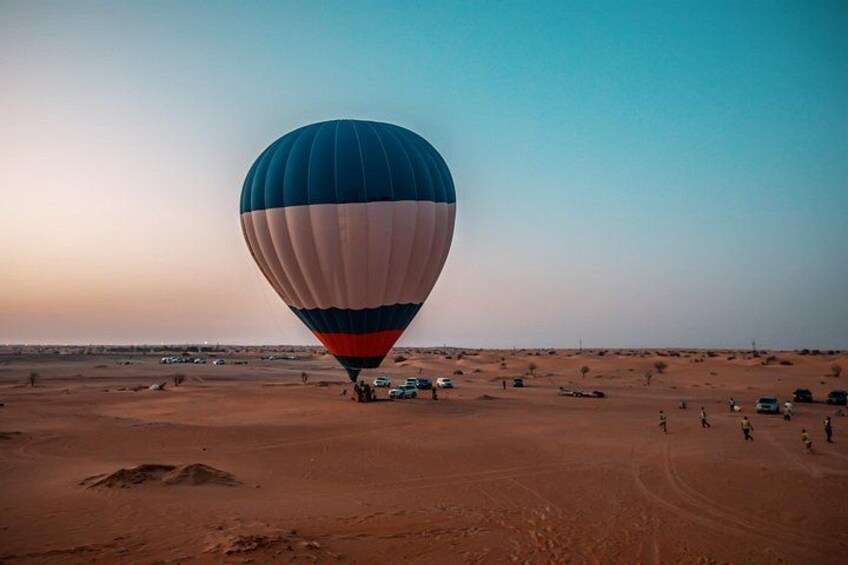 Un ballon à air chaud survolant un paysage désertique, avec une végétation clairsemée et un ciel dégagé. 4