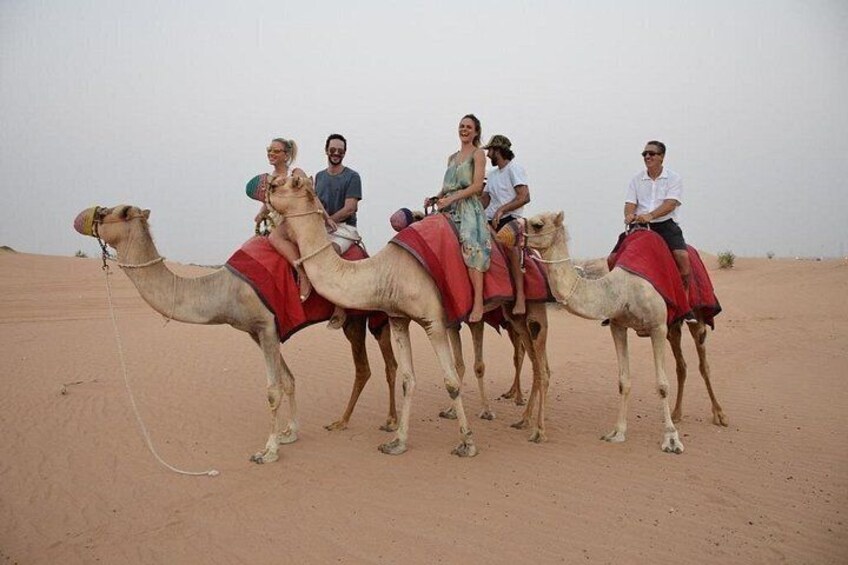 A group of people riding camels in a desert. 4