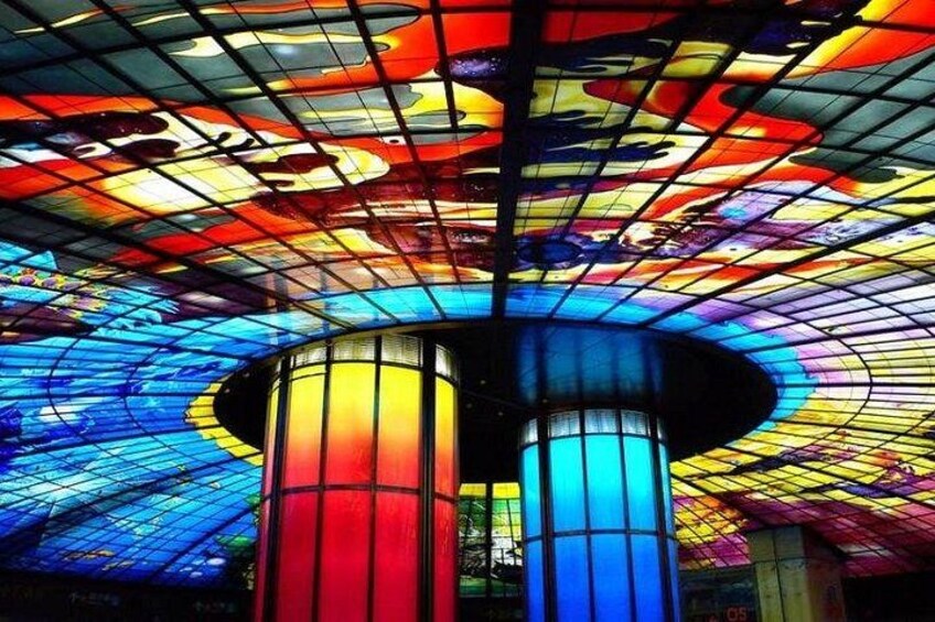 A colorful stained glass ceiling with geometric patterns and a central column. 5