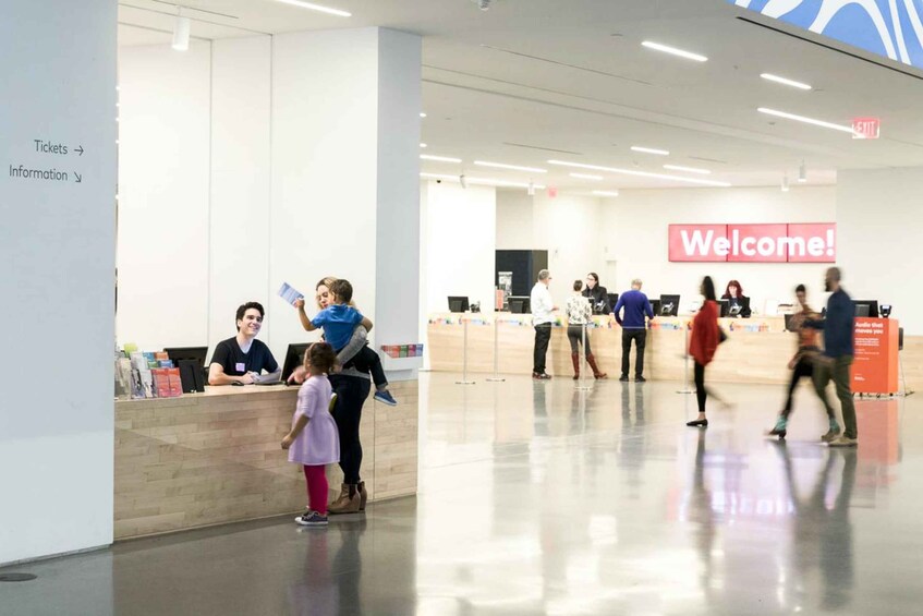 A modern airport check-in area with a 'Welcome!' sign, ticket counters, and people walking around. 5