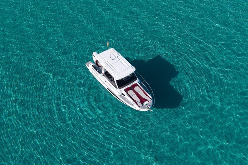 A white boat with a red stripe on the bow, floating on clear turquoise water. 3