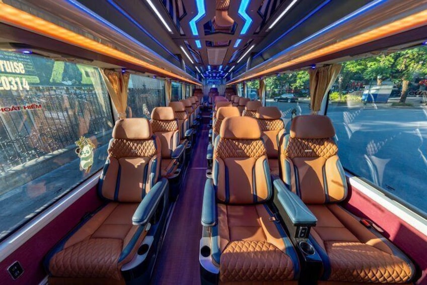 Interior de tren con asientos de cuero, compartimentos superiores para equipaje y una ventana que muestra un paisaje urbano. 5
