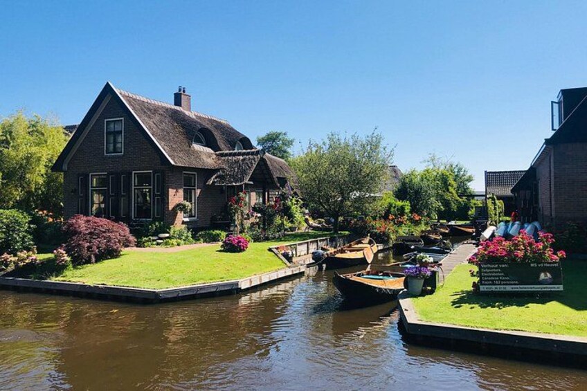 Un canal bordé de bateaux, une maison et une végétation luxuriante. 1