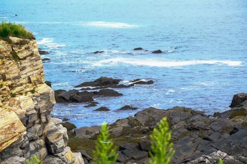 A coastal cliff with waves crashing against rocks. 2
