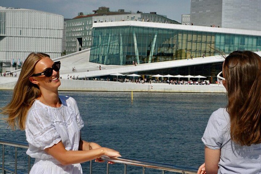 Two people standing by a waterfront with a modern glass building in the background. 2