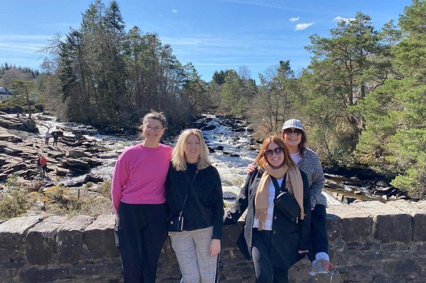 Un groupe de personnes se tient au bord d’une rivière aux rives rocheuses, avec des arbres en arrière-plan. 3