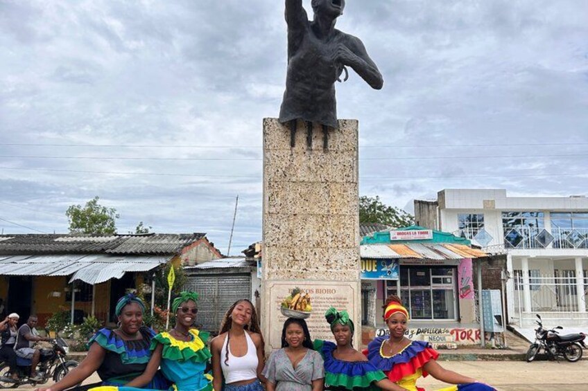 A statue with a group of people in colorful costumes in front of it. 3