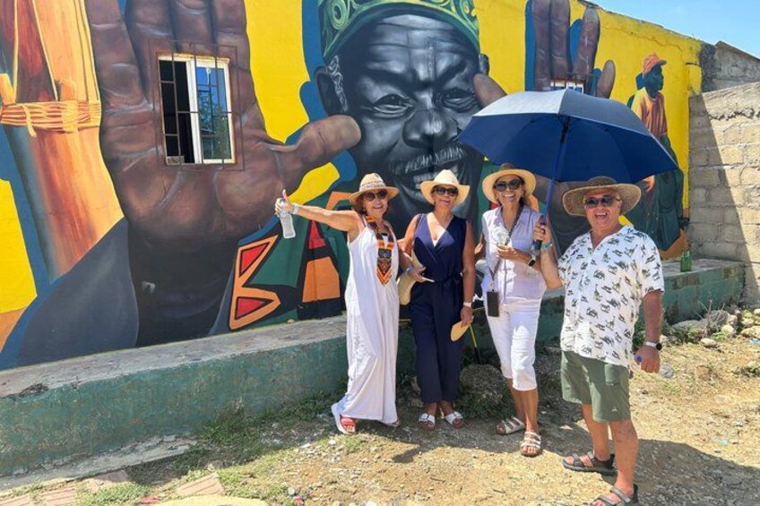 A mural with a large hand and a face, a window, and a group of people posing. 2