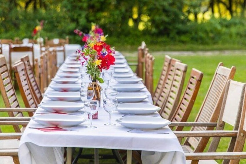 A long dining table set outdoors with chairs, white tablecloths, and floral centerpieces. 3