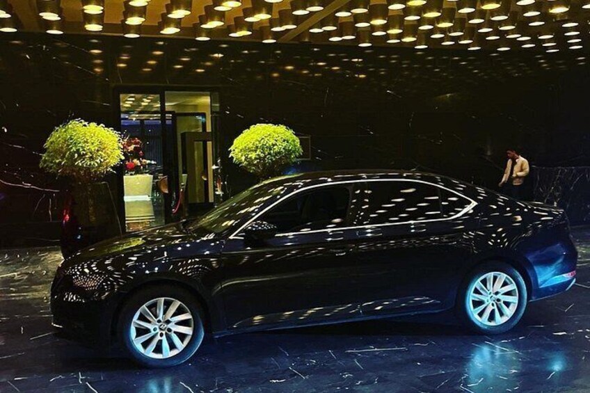 Un coche negro estacionado en el interior, con piso de mármol e iluminación circular en el techo. 2