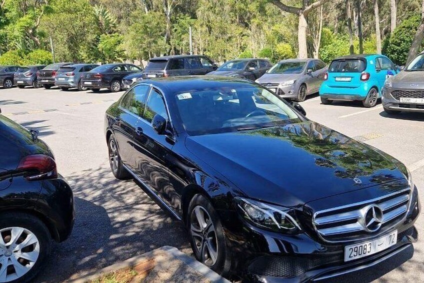 Un Mercedes-Benz negro estacionado en un estacionamiento, con árboles al fondo. 5
