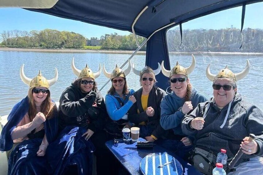 Un groupe de personnes à bord d’un bateau, portant des casques de Viking et buvant. 1