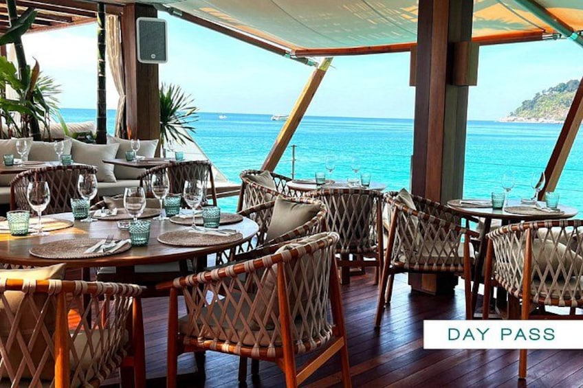 An outdoor dining area with wicker furniture and a view of the ocean. 5