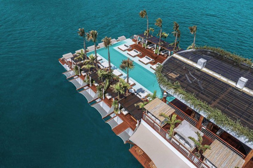 An aerial view of a resort with a pool, palm trees, and a wooden deck. 3