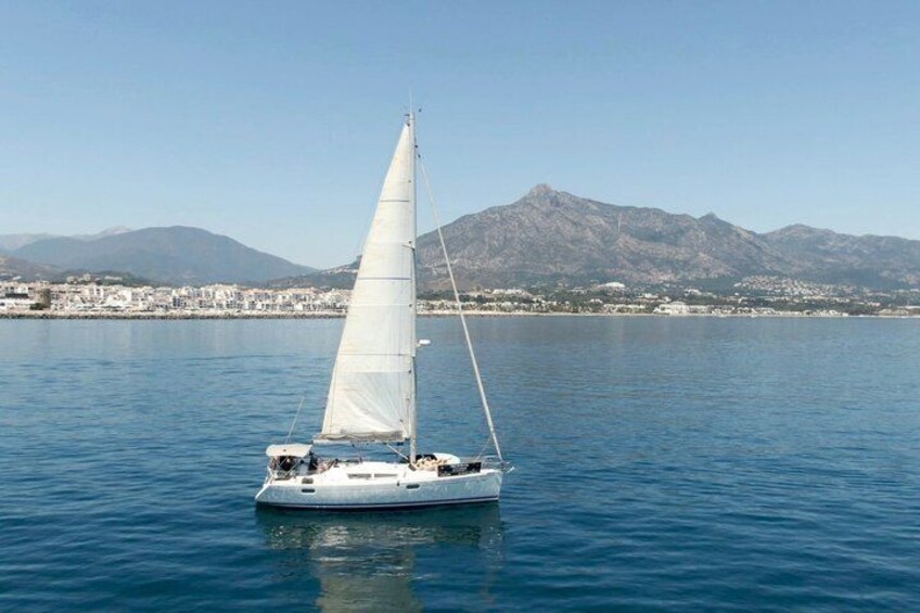 Un velero en aguas tranquilas con un paisaje montañoso al fondo. 1