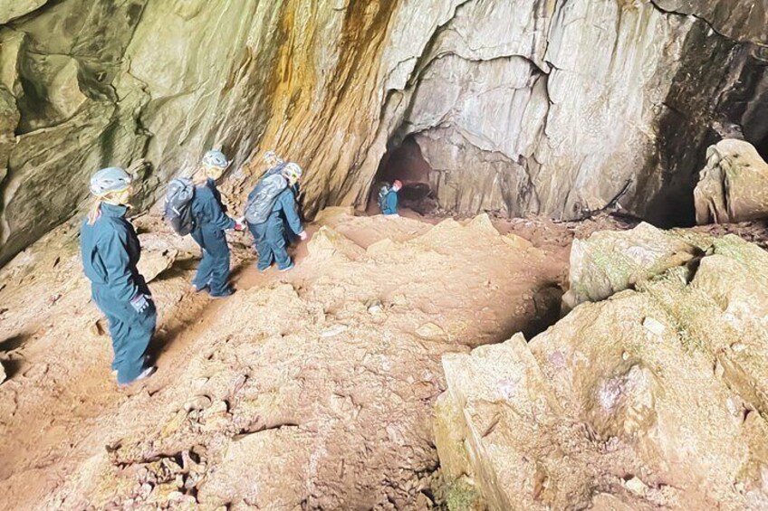 A group of people in protective gear exploring a rocky cave interior. 4
