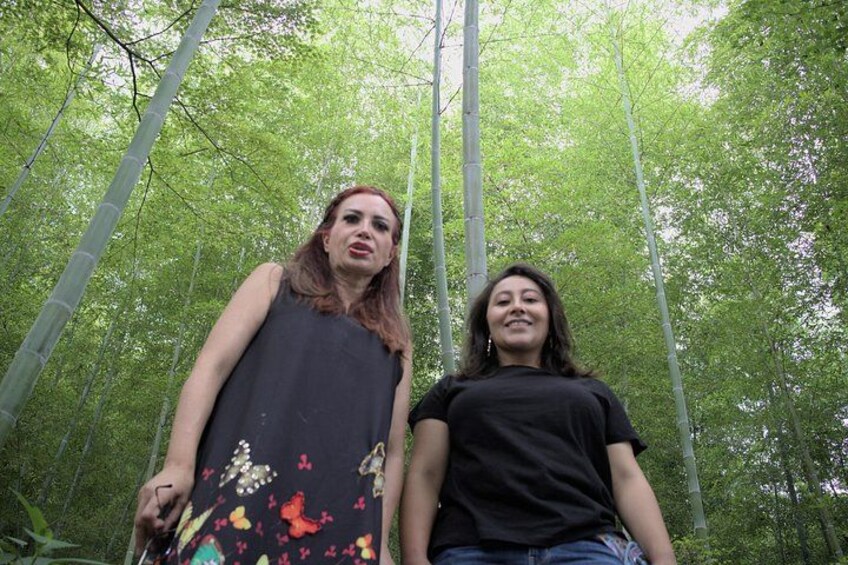 Two people standing in a forest with tall trees. 5