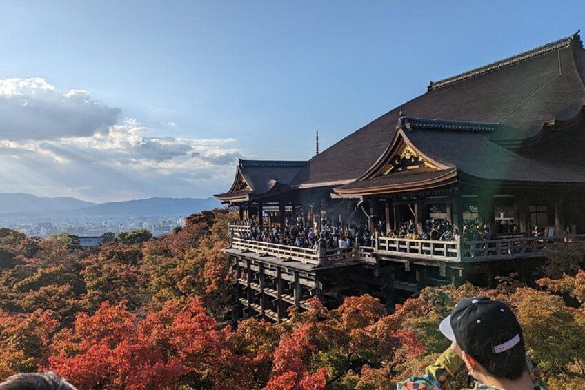 A traditional Japanese building with a wooden deck, surrounded by autumn foliage. 1