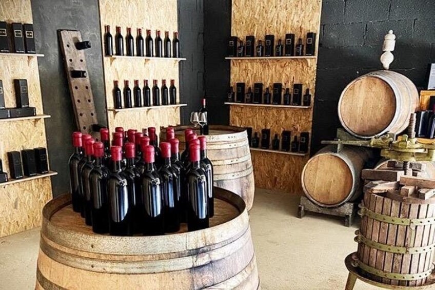 A wine cellar with wooden barrels and shelves of wine bottles. 4