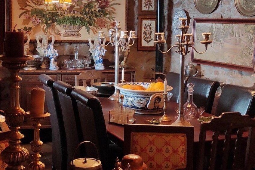 A dining room with a table set for four, featuring a vase of flowers, a candelabra, and a bowl of fruit. 5