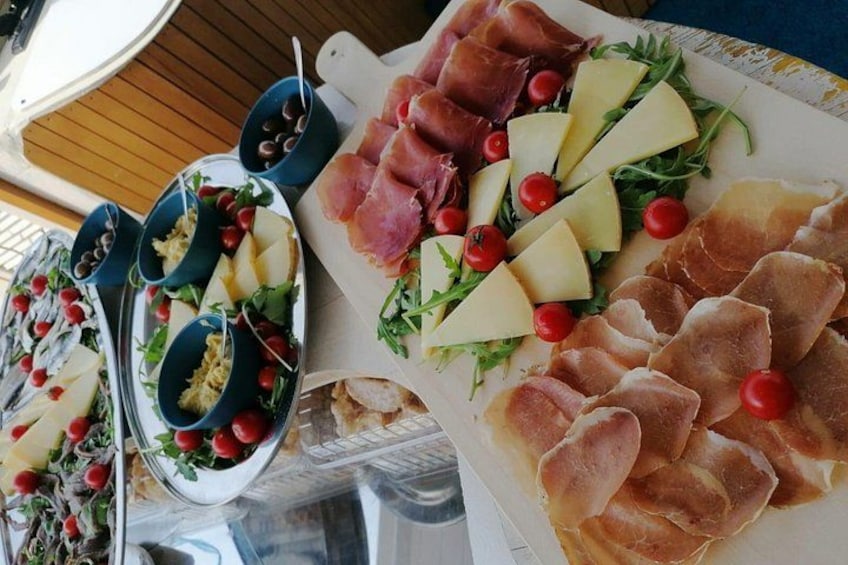 A variety of cheeses, cured meats, and garnishes on a wooden table. 4