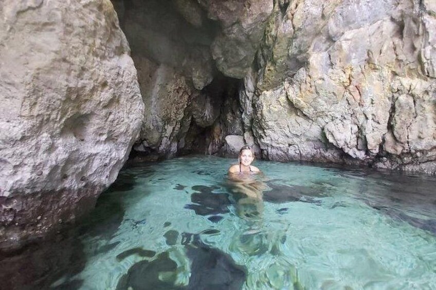 A person swimming in a natural pool surrounded by rocky cliffs. 1