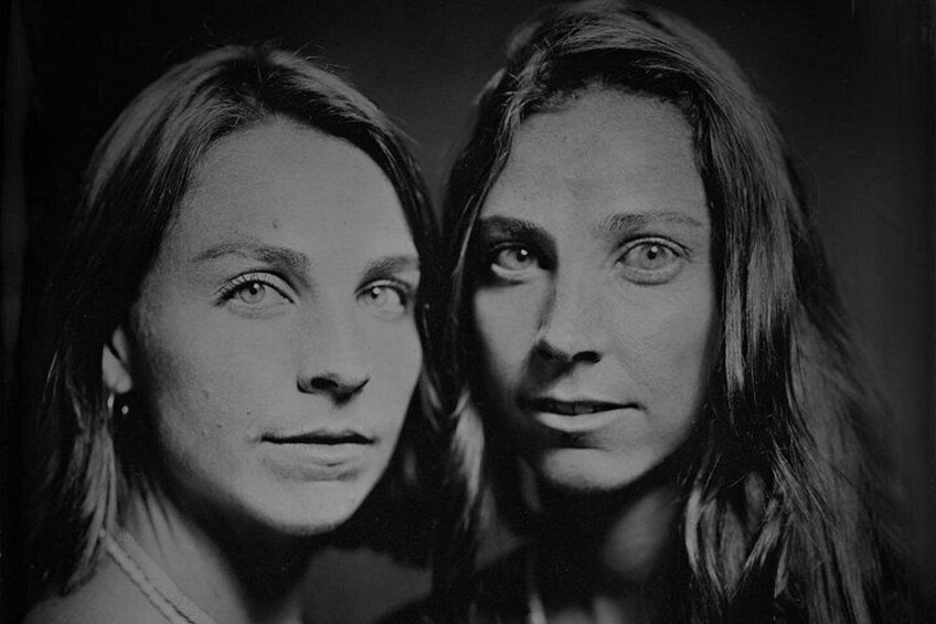 Two individuals with long hair, one with a visible earring, in a dimly lit setting. 3
