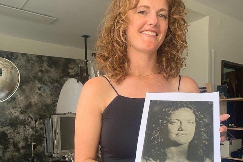 A person holding a photograph in a room with a modern kitchen in the background. 1