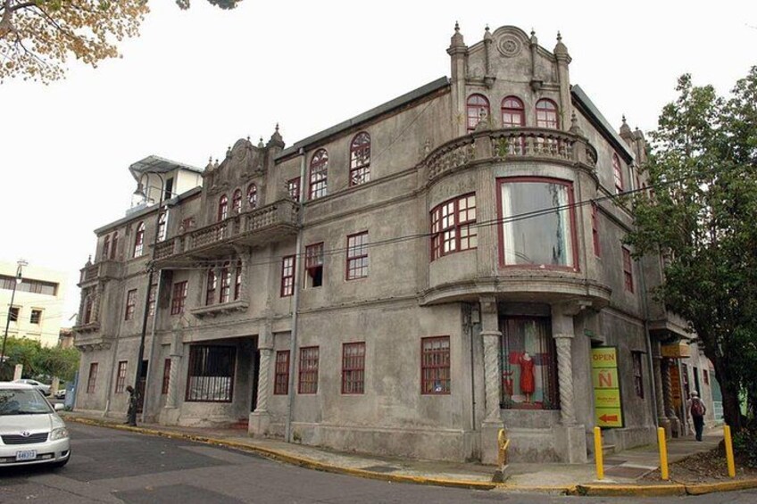 Un edificio histórico con arquitectura ornamentada, un ventanal grande y un letrero. 5