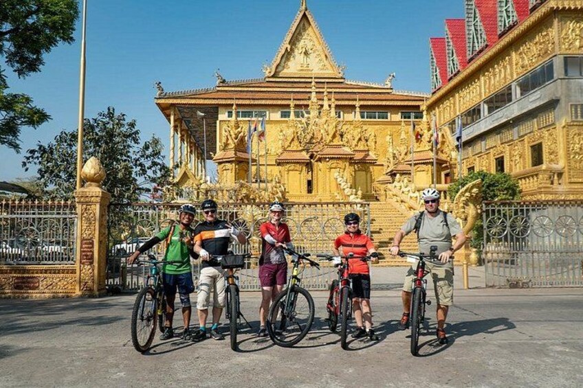 Un grupo de ciclistas frente a un templo dorado con arquitectura intrincada. 3