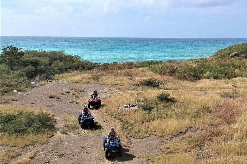 Three off-road vehicles on a dirt path with a coastal view. 3