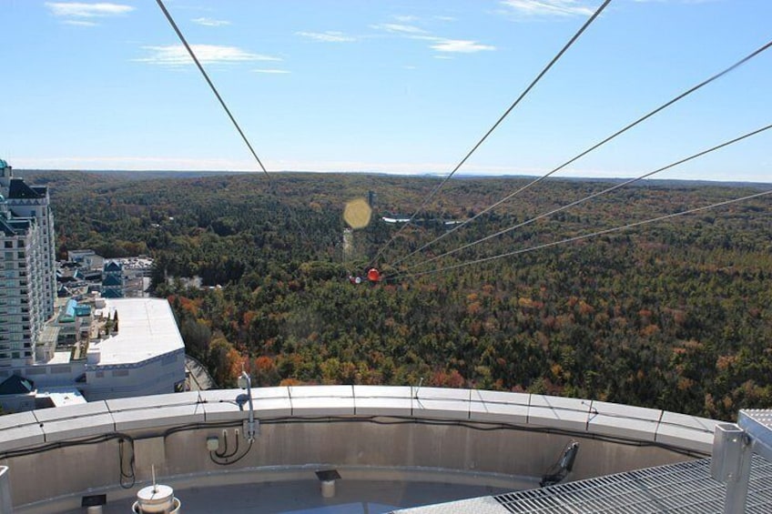 A cable car system with a view of a forested landscape and buildings in the background. 2