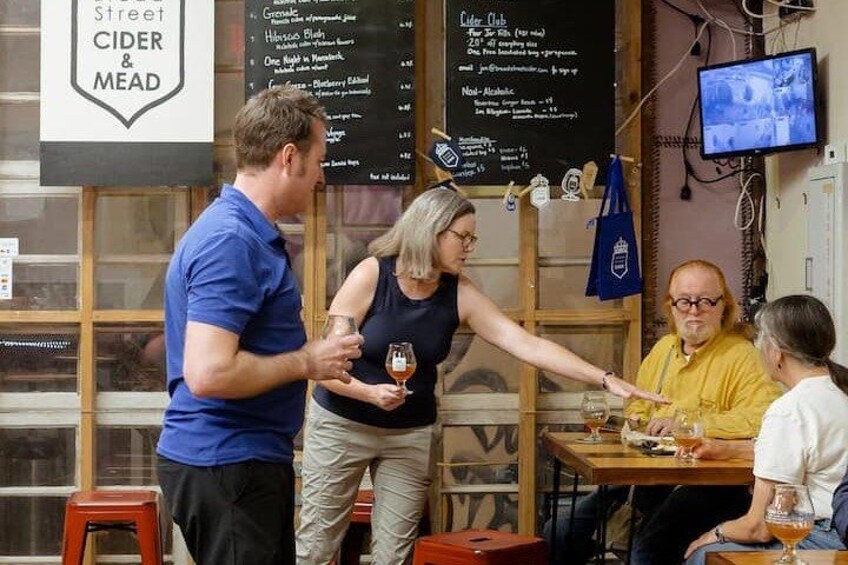 A group of people in a bar setting, with a menu board and a television in the background. 4