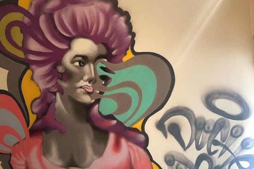 Ein Graffiti-Mural mit abstrakten Formen und einer Gestalt mit lila Haaren. 3