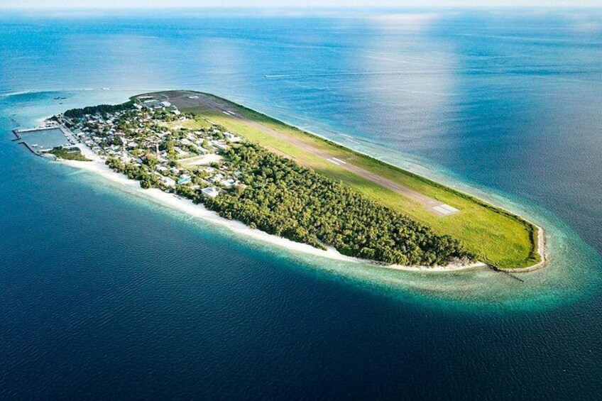 Une vue aérienne d’une petite île, avec un chenal aux eaux cristallines, une végétation luxuriante et quelques bâtiments. 4