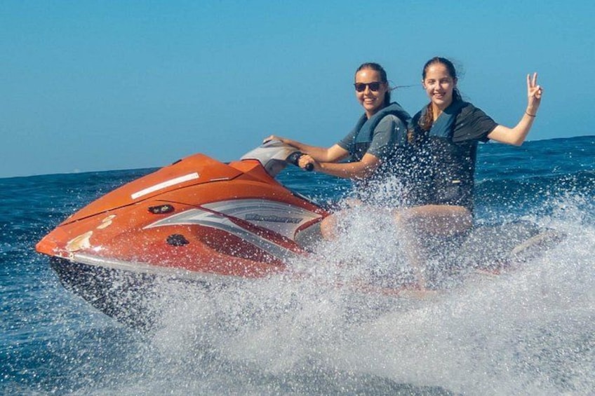 Two people jet-skiing on a body of water. 2