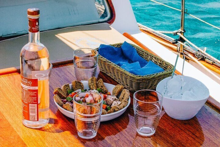 A bottle of liquor, a plate of snacks, glasses, and a bowl of ice on a boat deck. 5