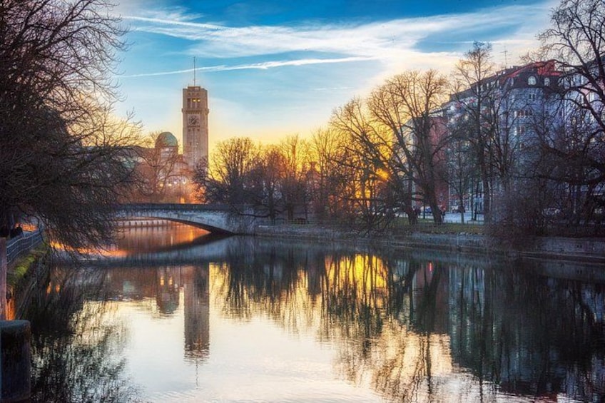 A calm river with a bridge, trees, and buildings reflecting in the water. 5