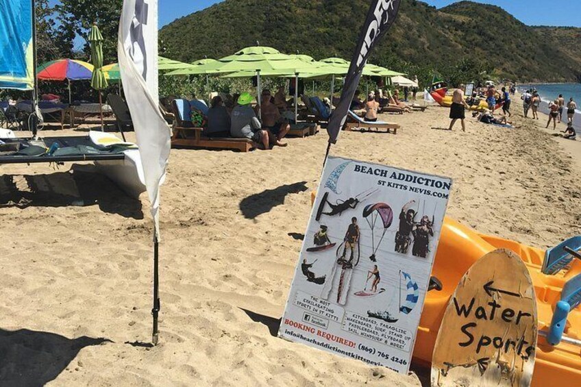 Een strand met parasols, ligbedden en een bord voor watersport. 1