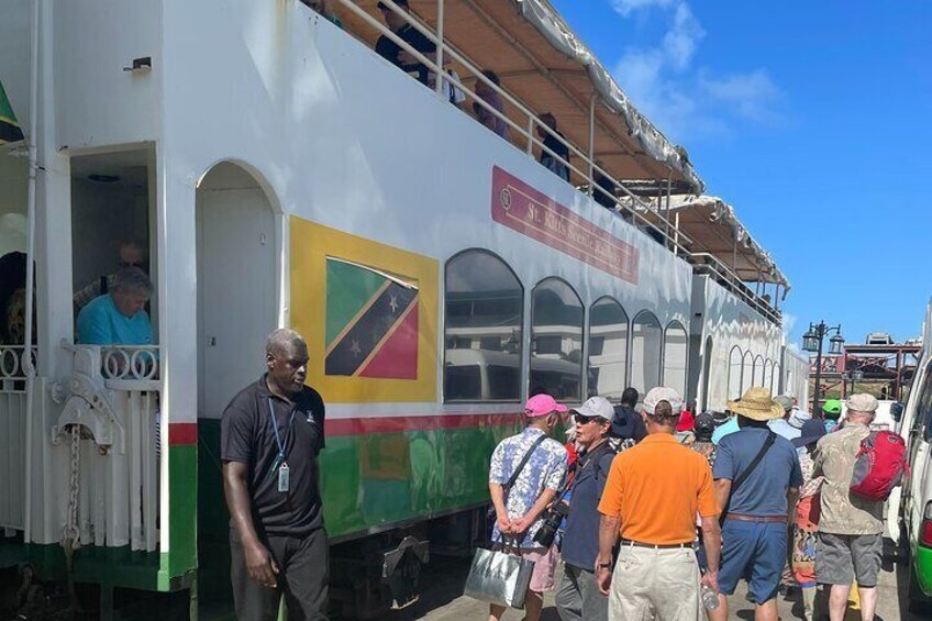 A colorful bus with a flag, passengers boarding, and a man standing in front. 5