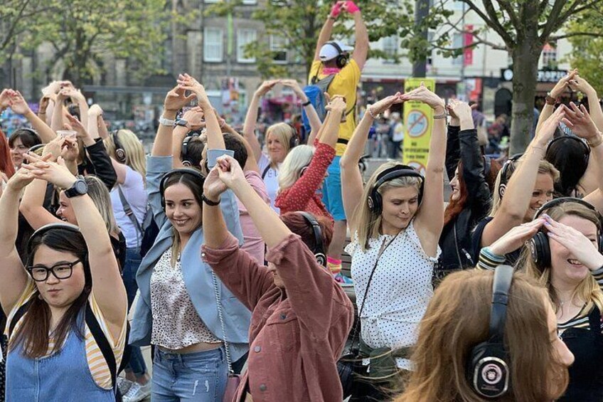 Een menigte mensen heft hun handen gezamenlijk in de lucht, mogelijk tijdens een openbaar evenement of viering. 5