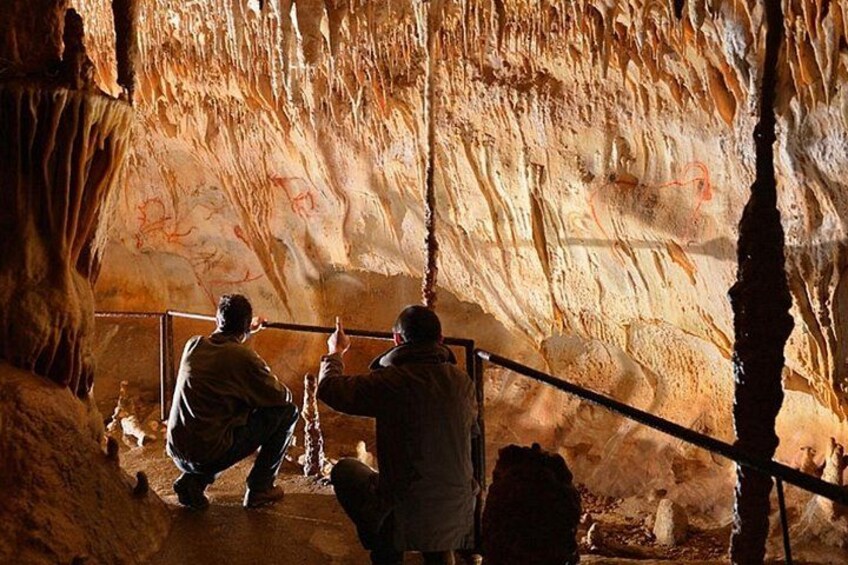 A cave with stalactites and stalagmites, and two people examining the formations. 3
