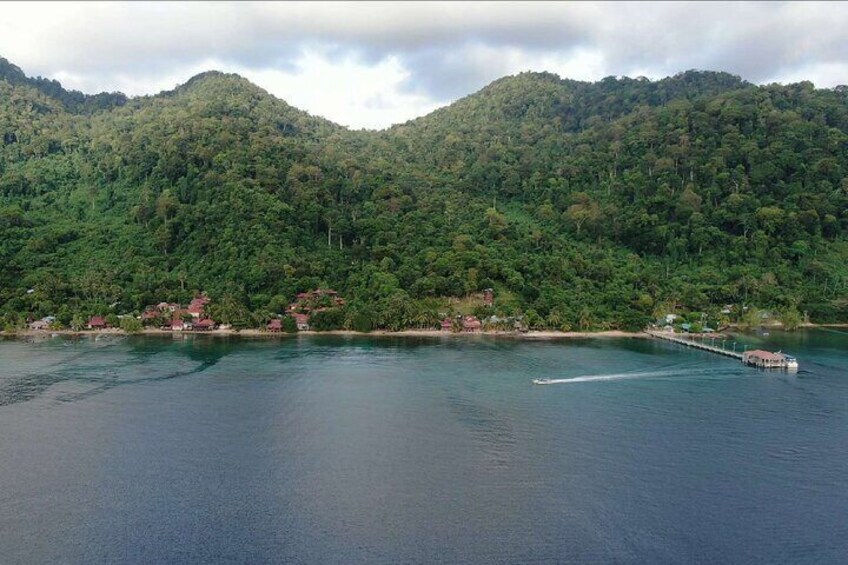 A calm lake with a pier extending into the water, surrounded by lush green hills. 2