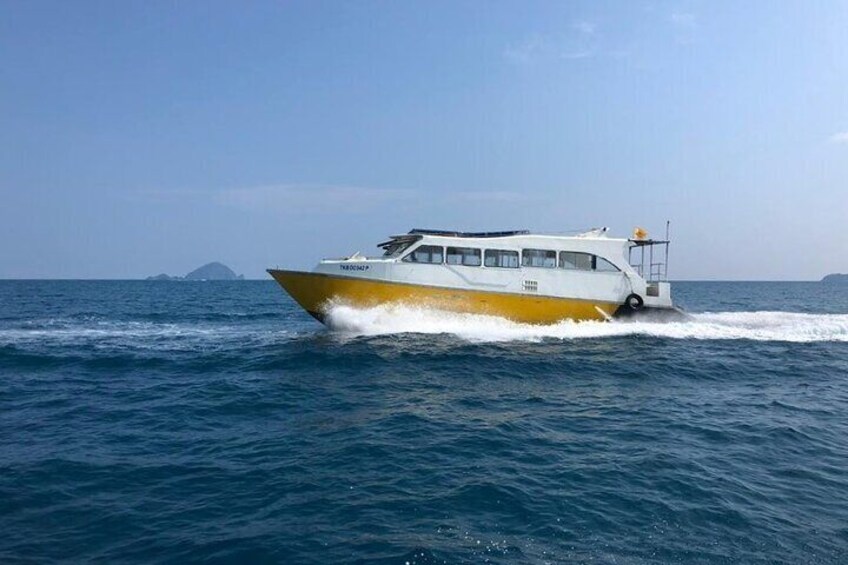 A white and yellow boat moving through the ocean with a clear sky and distant islands. 1