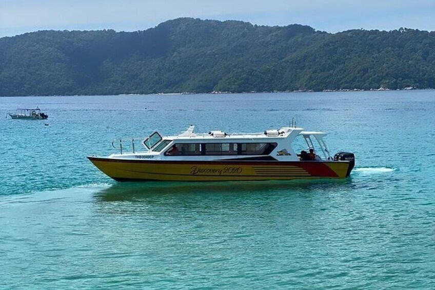 A yellow and red boat named 'Discovery' on calm waters with a forested island in the background. 5
