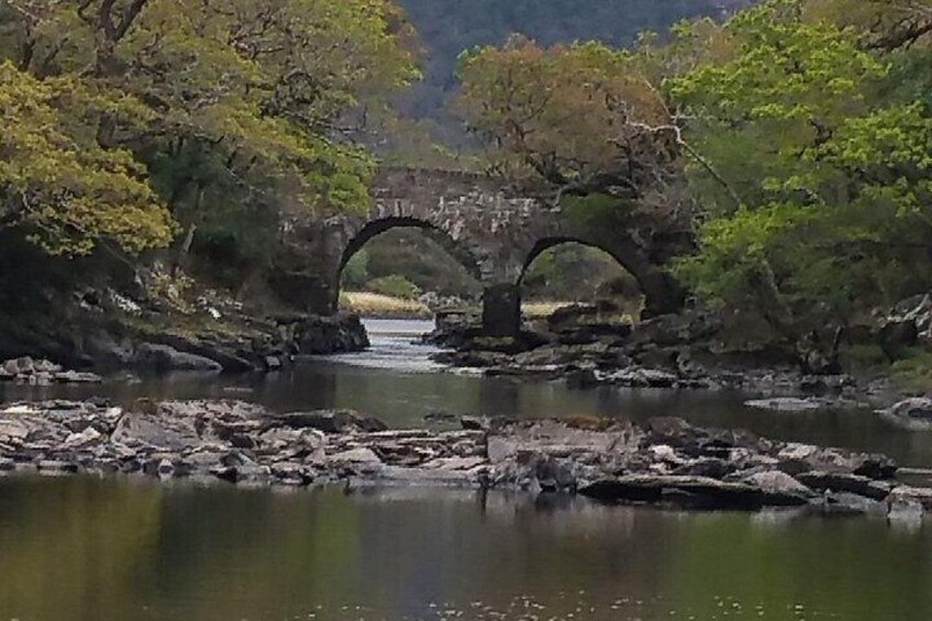 Un puente de piedra sobre un río, rodeado de árboles y terreno rocoso. 4