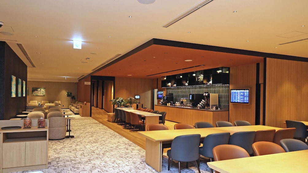 A modern conference room with a long table, multiple chairs, a reception desk, and a bar area. 2