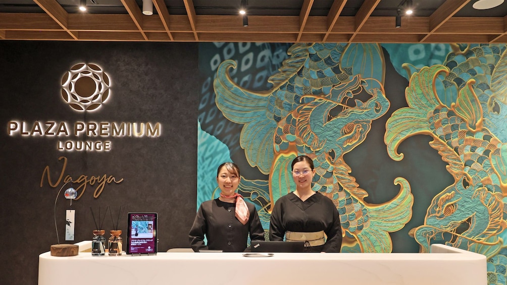 A reception desk with a decorative wall featuring a dragon mural and the text 'PLAZA PREMIUM LOUNGE Nagoya'. 4