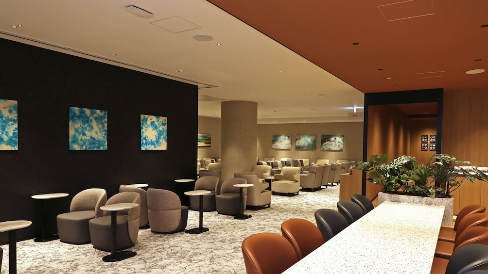 A modern interior with a long reception desk, multiple seating areas, and abstract wall art. 3